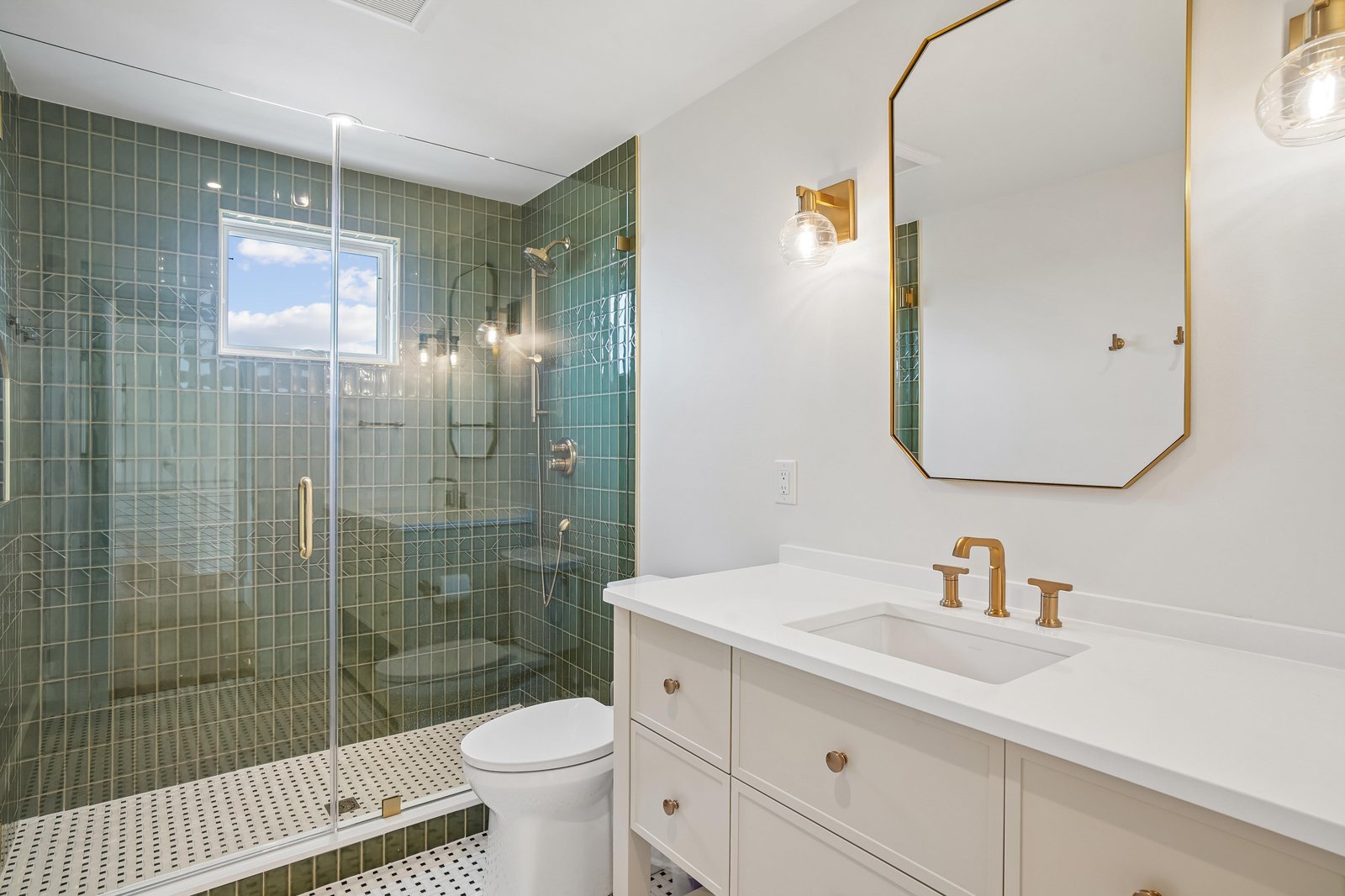 Step into your beautifully appointed bathroom, where emerald green tile meets gleaming brass accents. The spacious walk-in shower invites you to unwind after a day of exploring.