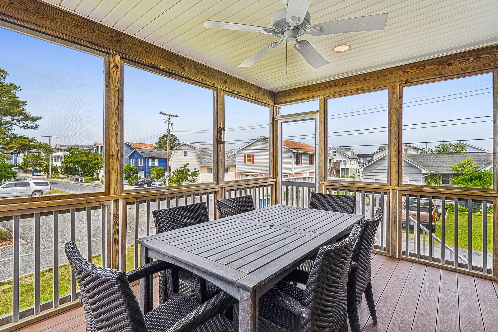 A screened porch with neighborhood views where you can enjoy your morning coffee or evening meals in the fresh air, with ceiling fan and ample seating for your group.