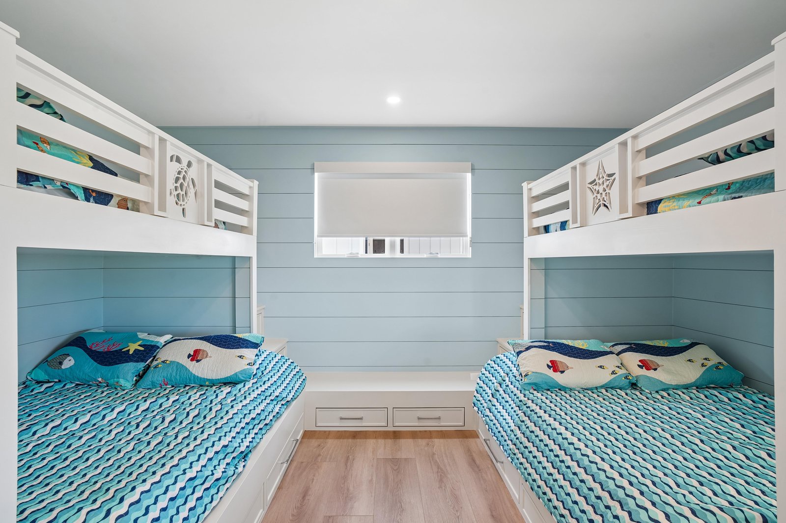 Your little ones will love this charming coastal bunk room, where soft ocean-blue walls and cheerful sea-themed bedding create the perfect hideaway for restful nights and dreamy adventures.