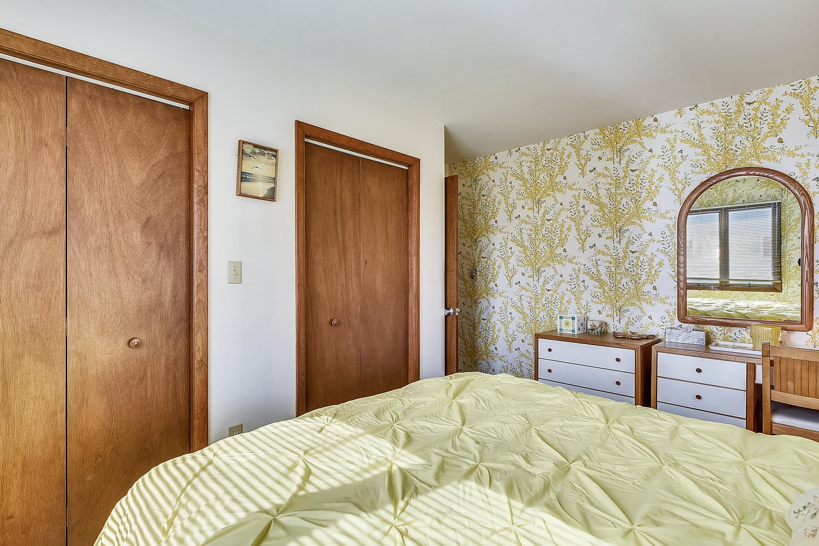 Your cheerful bedroom features a soft bed dressed in fresh linens, charming floral wallpaper, and plenty of storage space to keep your belongings organized during your stay.