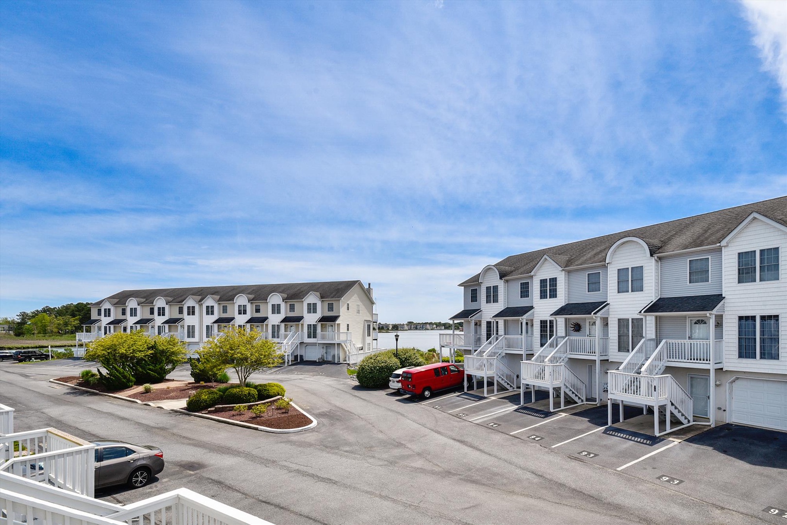 Multi-unit residential property featuring townhouse-style accommodations with ground-level parking and landscaped common areas under a bright coastal sky.
