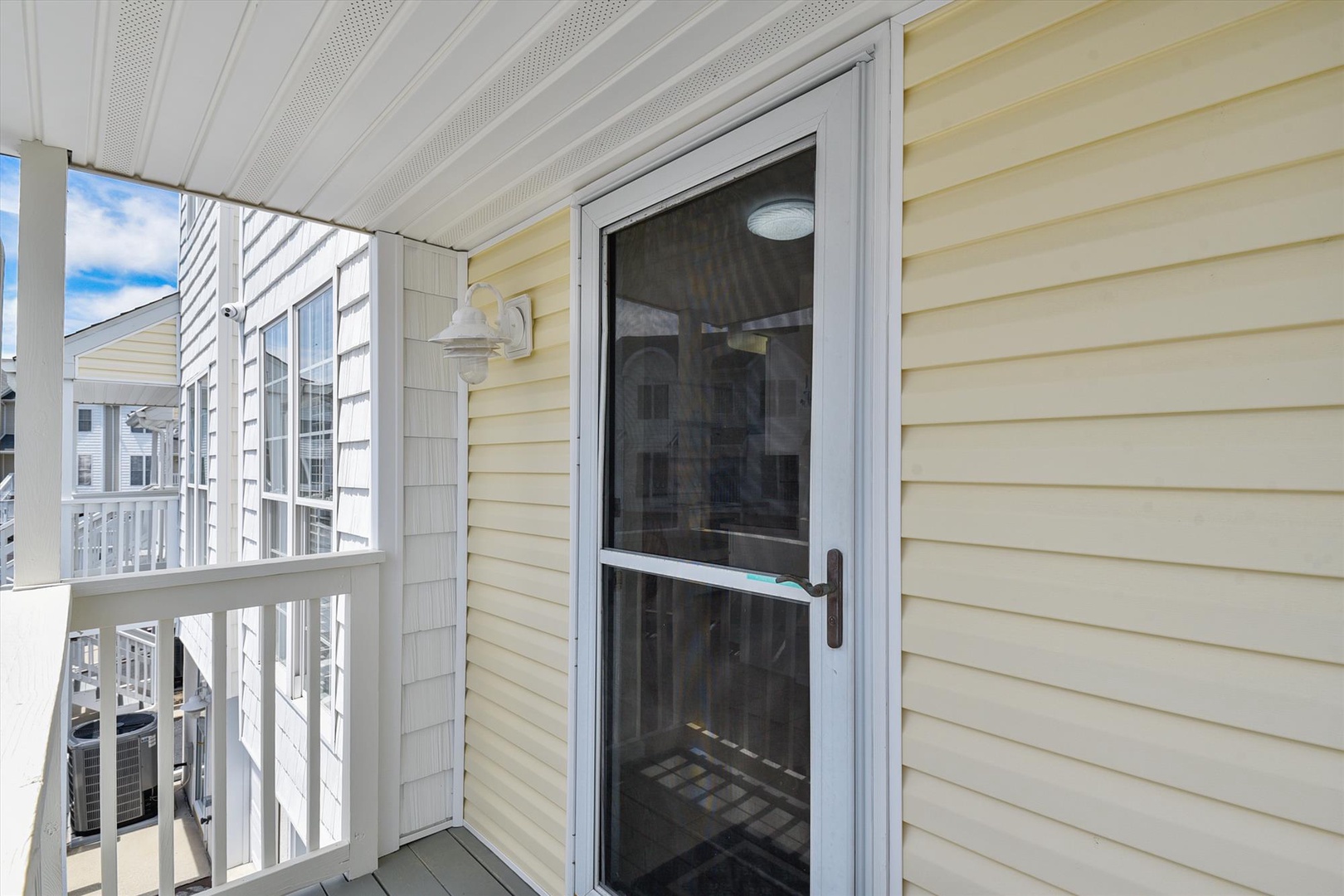 Covered porch entry with coastal residential architecture and neighborhood views, positioned at the property's side access point.