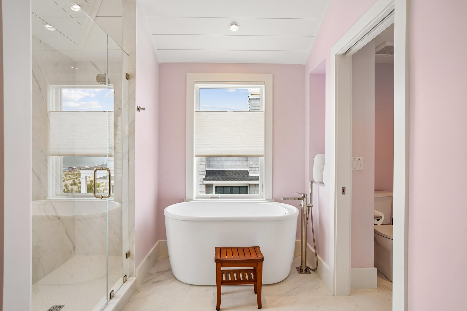 Sink into your own private spa retreat where soft blush tones meet a soaking tub built for pure relaxation. Light streams through the window, inviting you to unwind after a day of coastal adventures.
