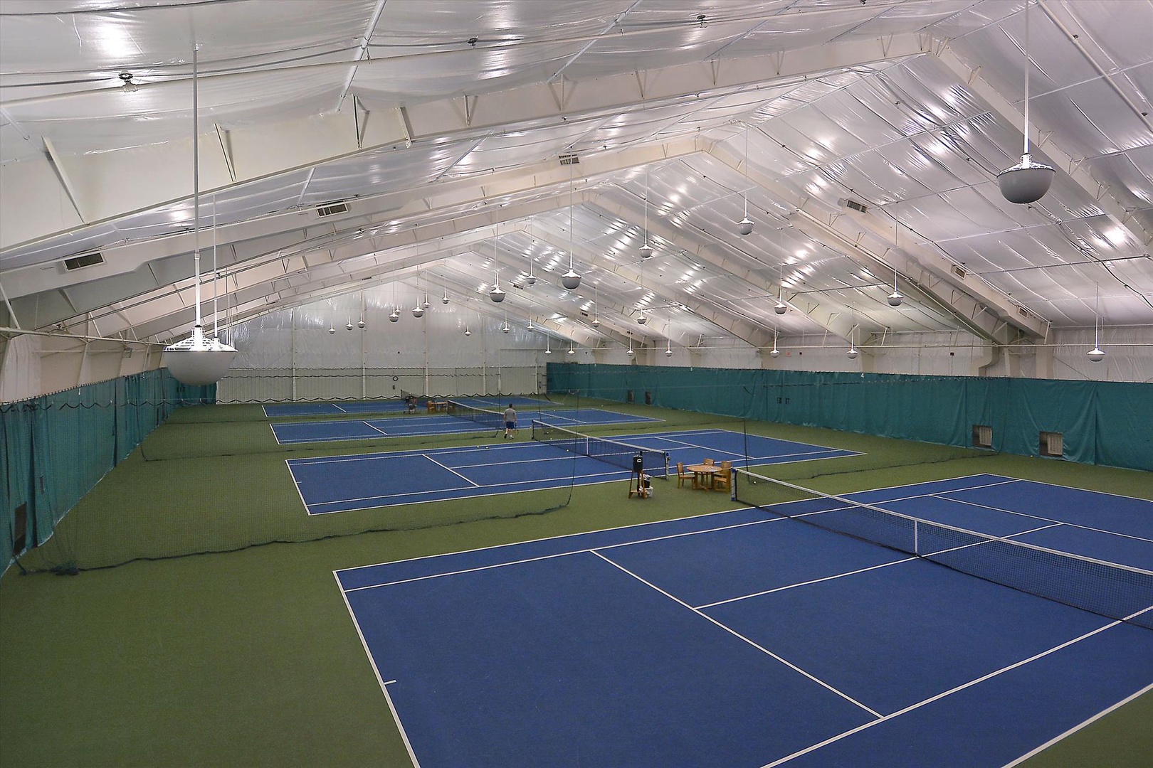 Indoor tennis courts with pristine blue surfaces await your game, offering year-round play in a climate-controlled setting. Perfect for sharpening your skills or enjoying a friendly match.