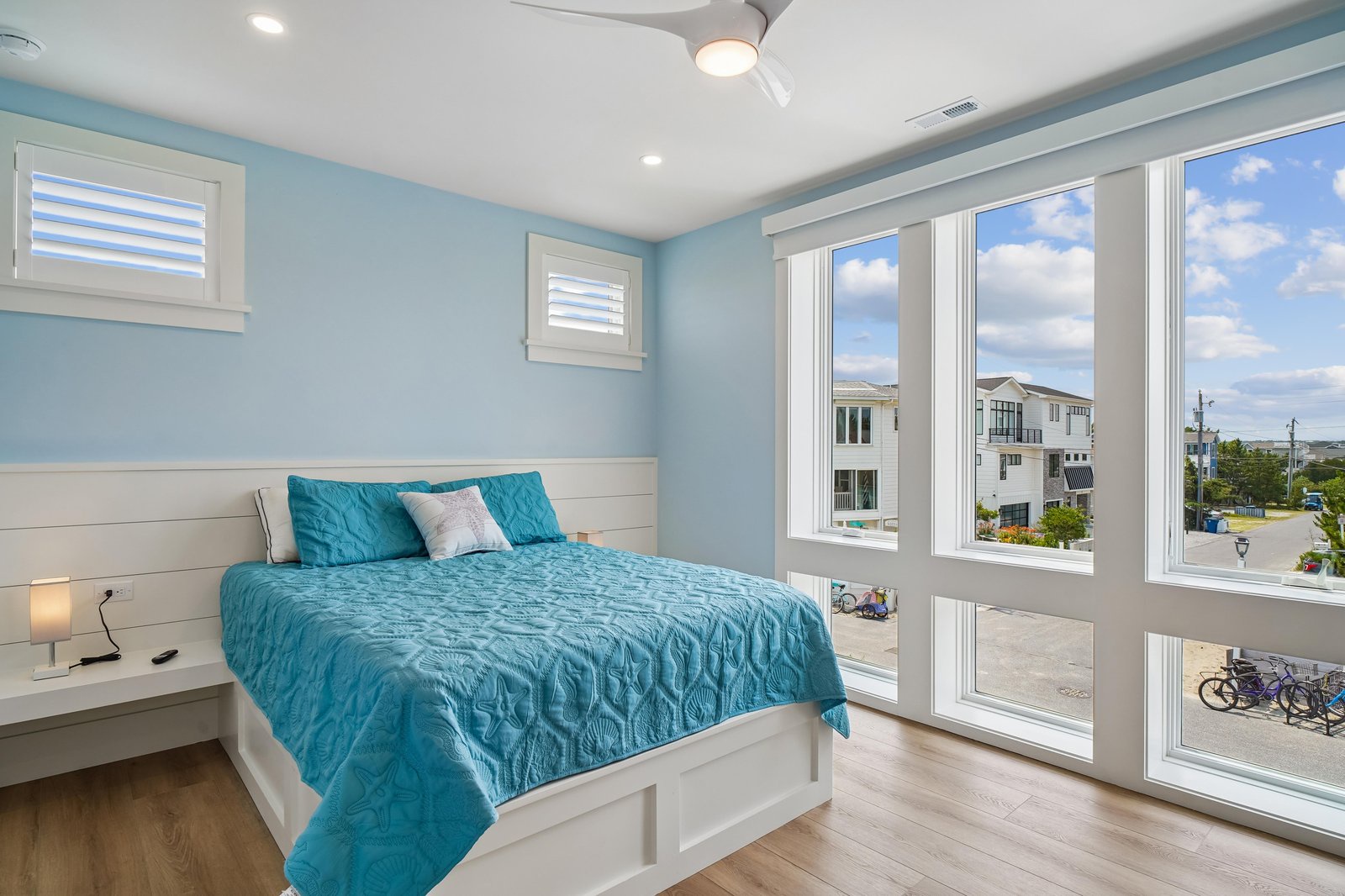 Drift off in your serene coastal-inspired bedroom, where soothing blue tones and natural light from expansive windows create a peaceful escape after your beach adventures.