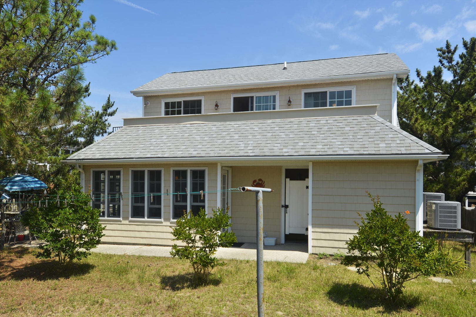 A charming two-story beach house with natural wood siding, nestled among coastal pines. Features include a covered porch area and air conditioning for your comfort year-round.