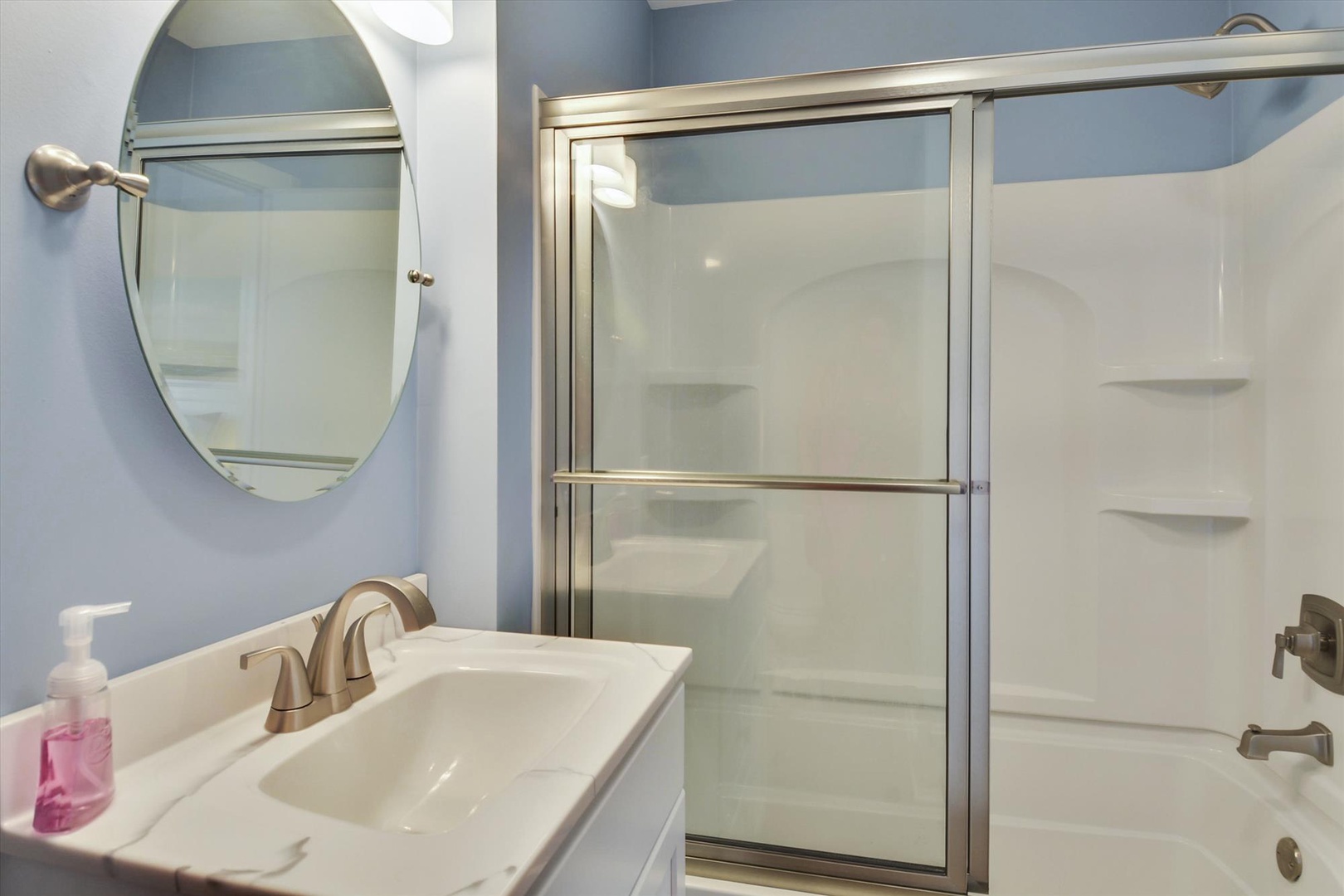 Freshen up in your private bathroom with a sleek glass-enclosed shower, modern fixtures, and calming blue tones that make mornings feel effortless.