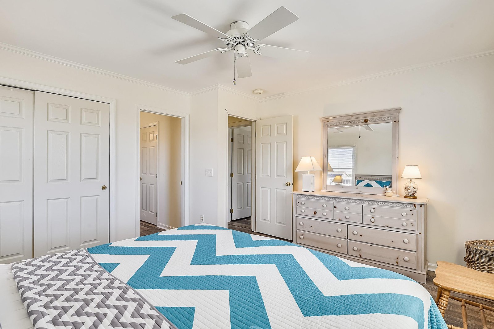 Your bright coastal bedroom awaits with cheerful blue and white linens, ceiling fan, and plenty of storage space to settle in and unwind.