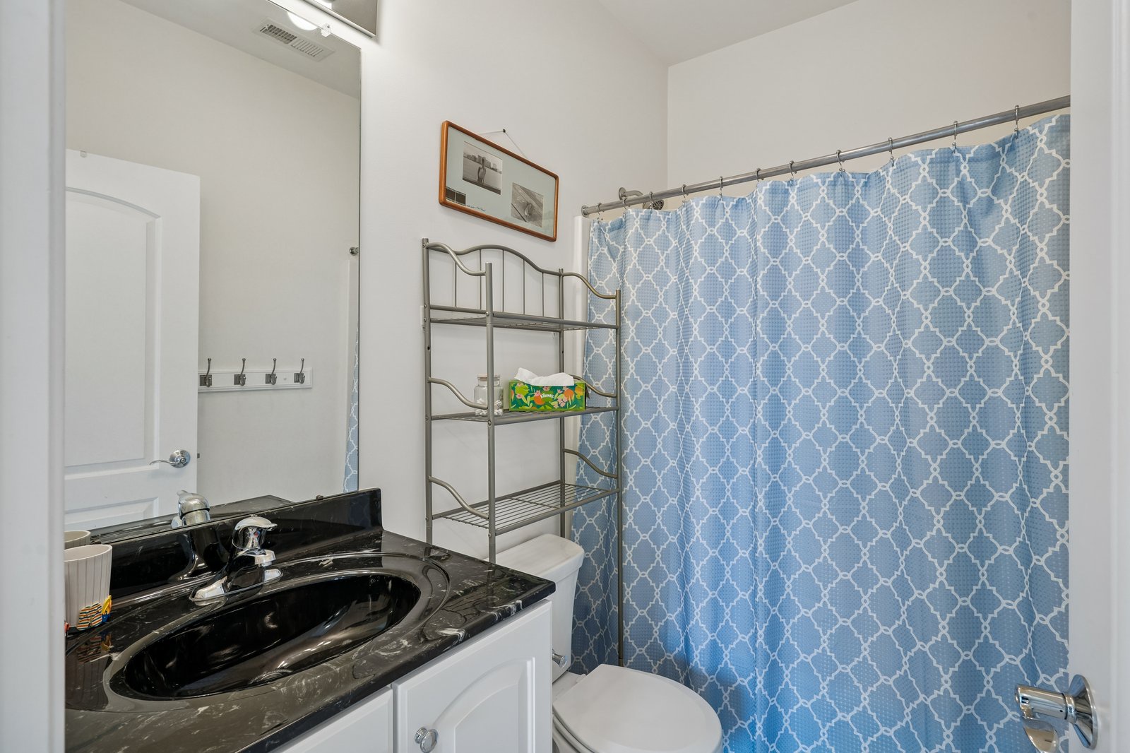 Step into your well-appointed bathroom featuring a stylish blue geometric shower curtain and elegant granite countertops for your comfort.