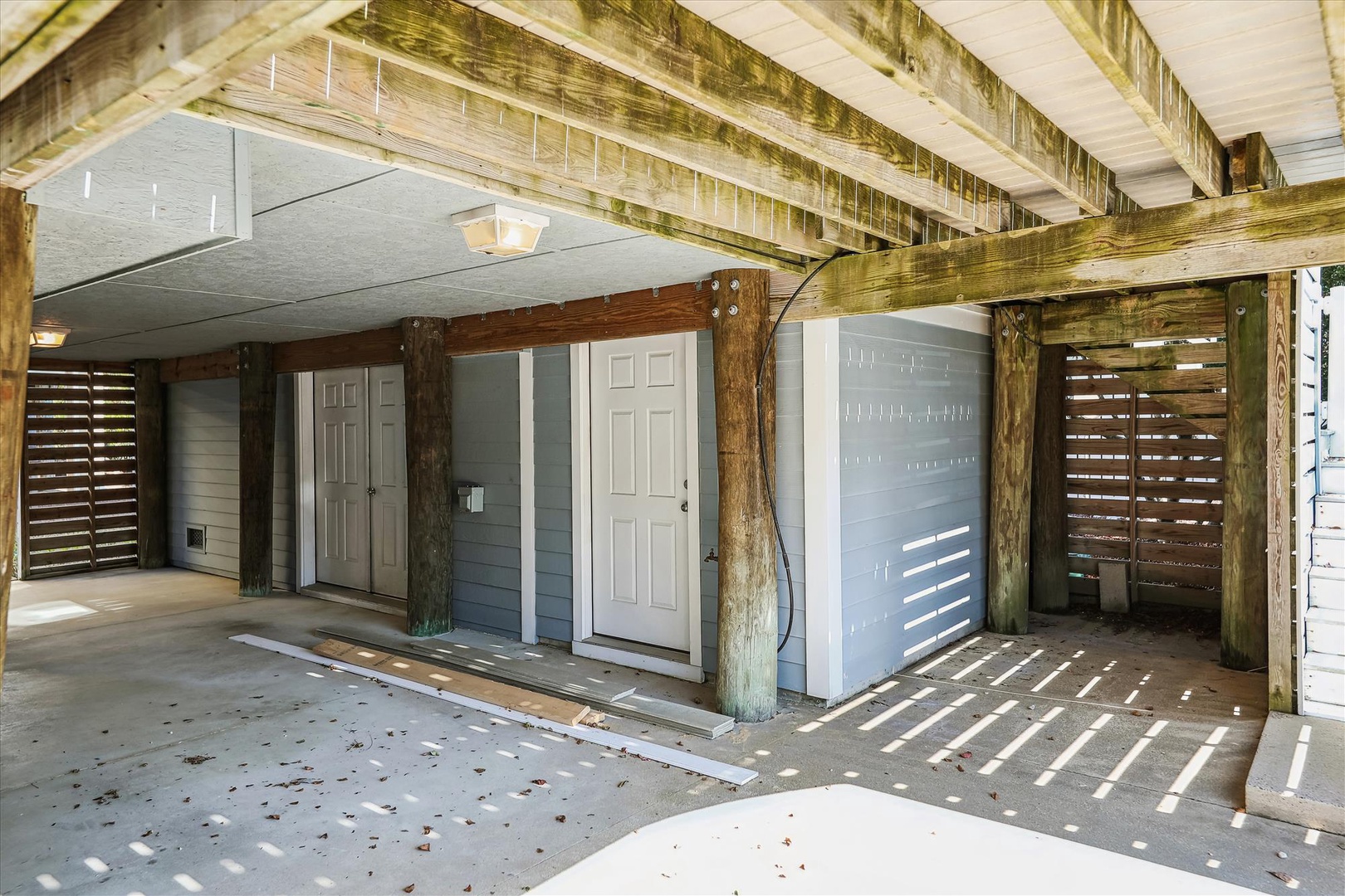 The covered ground-level area provides easy access to storage and entry doors, protected by natural timber columns and a well-maintained ceiling for your arrival and belongings.
