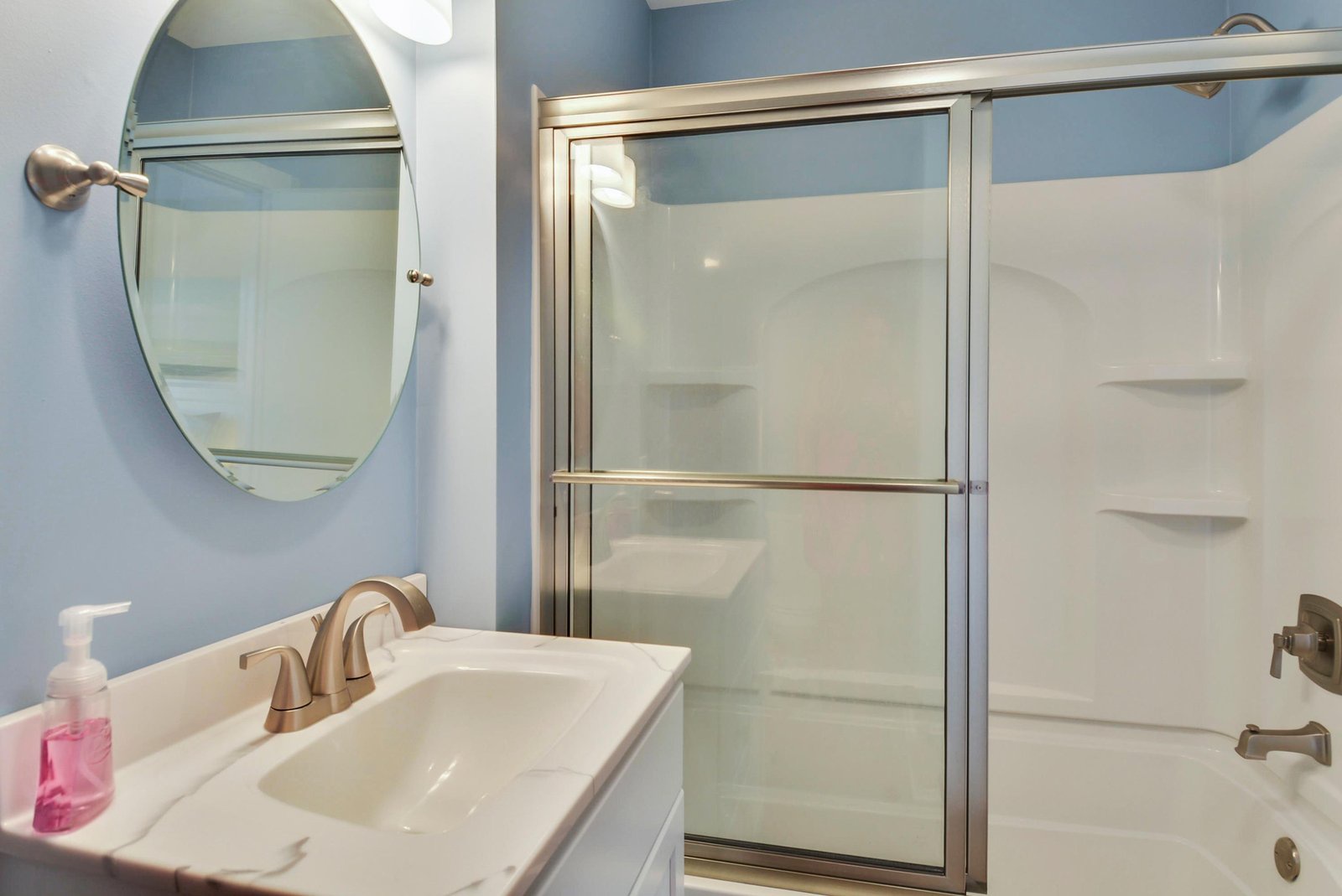 Refresh in your private bathroom with a glass-enclosed tub-shower combo, framed by soothing blue walls and a sleek vanity for easy mornings.