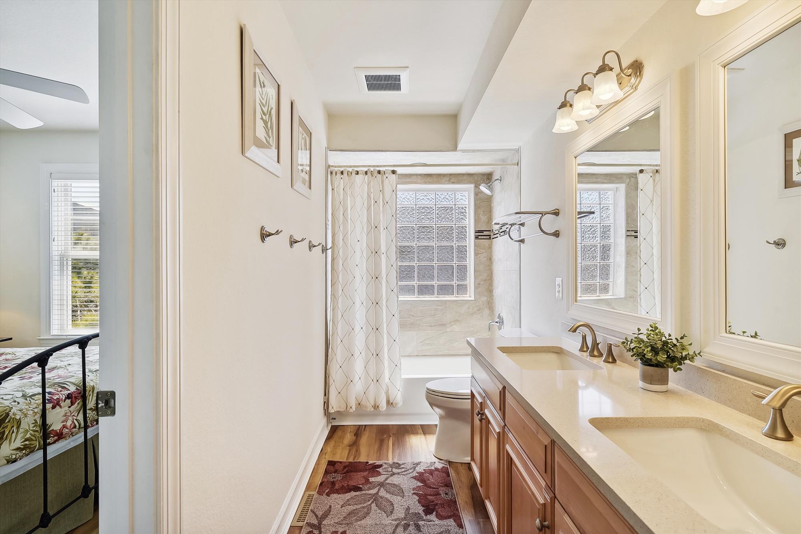 Unwind in your elegant ensuite bathroom featuring a dual-sink vanity, a bathtub with natural light, and warm wood flooring that adds comfort to your morning and evening routines.