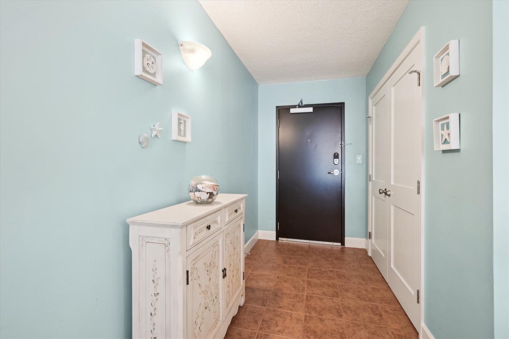 Step into your coastal-inspired entryway, where soothing seafoam walls and charming artwork create a peaceful first impression of your beachside retreat.