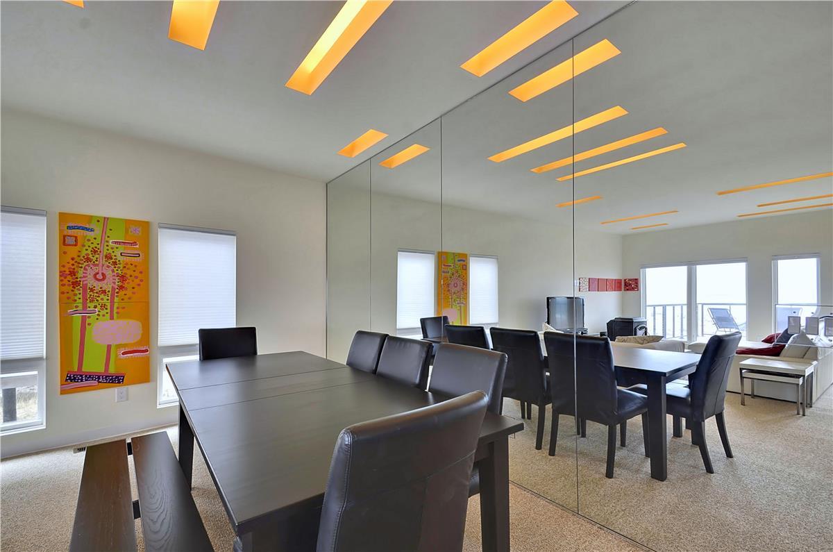 A sleek, modern meeting space with striking orange ceiling accents and floor-to-ceiling windows inviting natural light. The mirrored wall doubles the sense of space, perfect for productive gatherings.