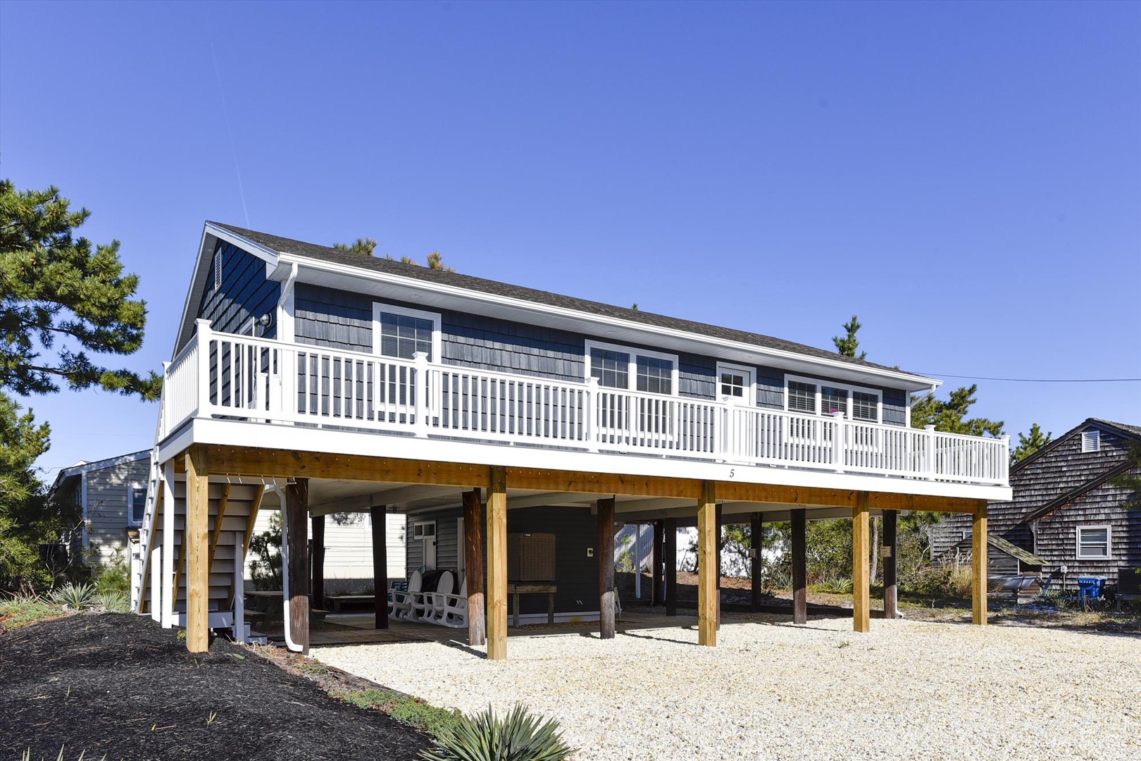 A charming coastal cottage elevated on sturdy wooden pilings with a spacious wraparound deck, offering you easy parking and outdoor space to unwind after beach days.