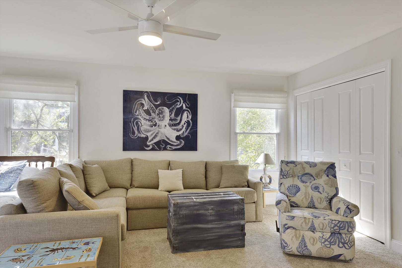 Your coastal-inspired living room awaits with comfortable sectional seating, nautical artwork, and natural light streaming through large windows. Perfect for relaxing after beach days.