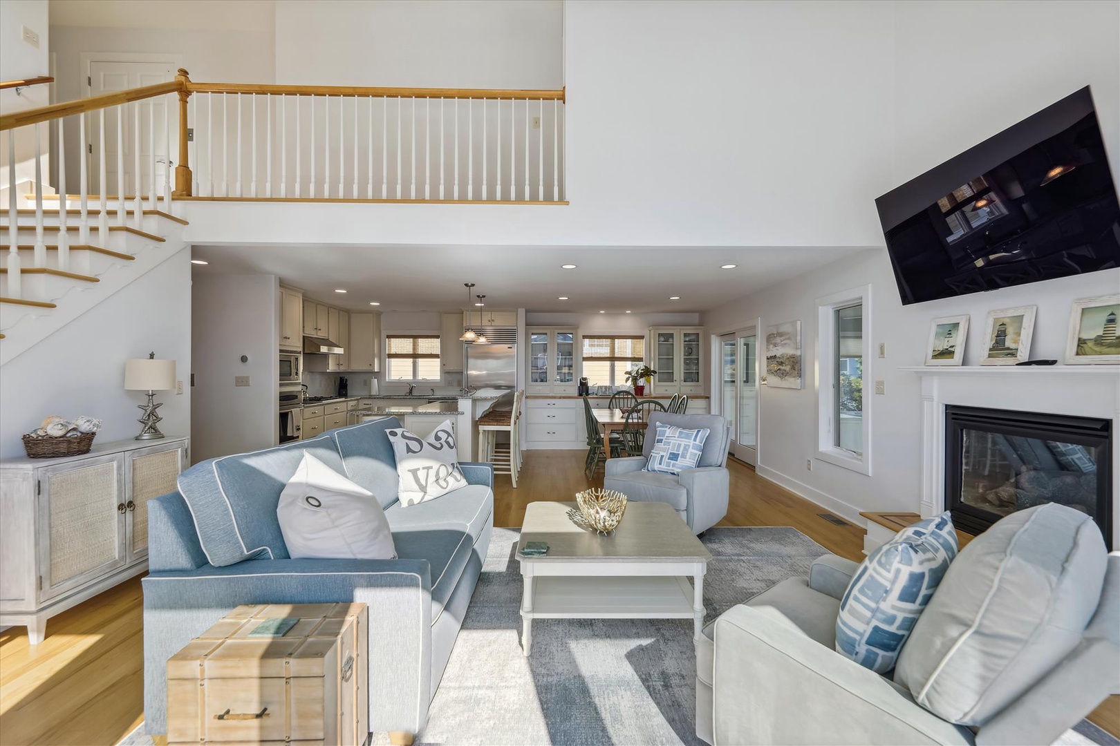 Step into an open, airy space where comfort meets coastal charm. Relax on plush sofas, warm your toes by the fireplace, and enjoy seamless flow into a bright, fully-equipped kitchen.