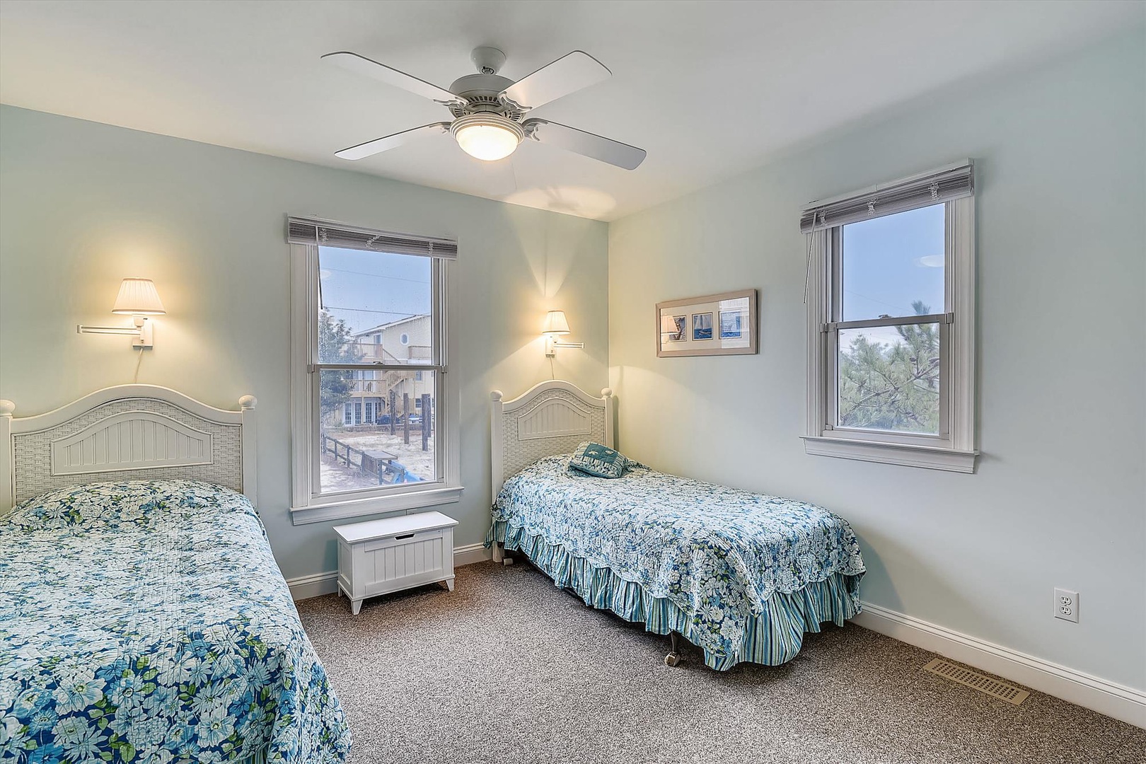 Sink into crisp coastal linens in your serene twin bedroom, where soft blues and gentle breezes from the ceiling fan create your perfect sanctuary for rest and relaxation.