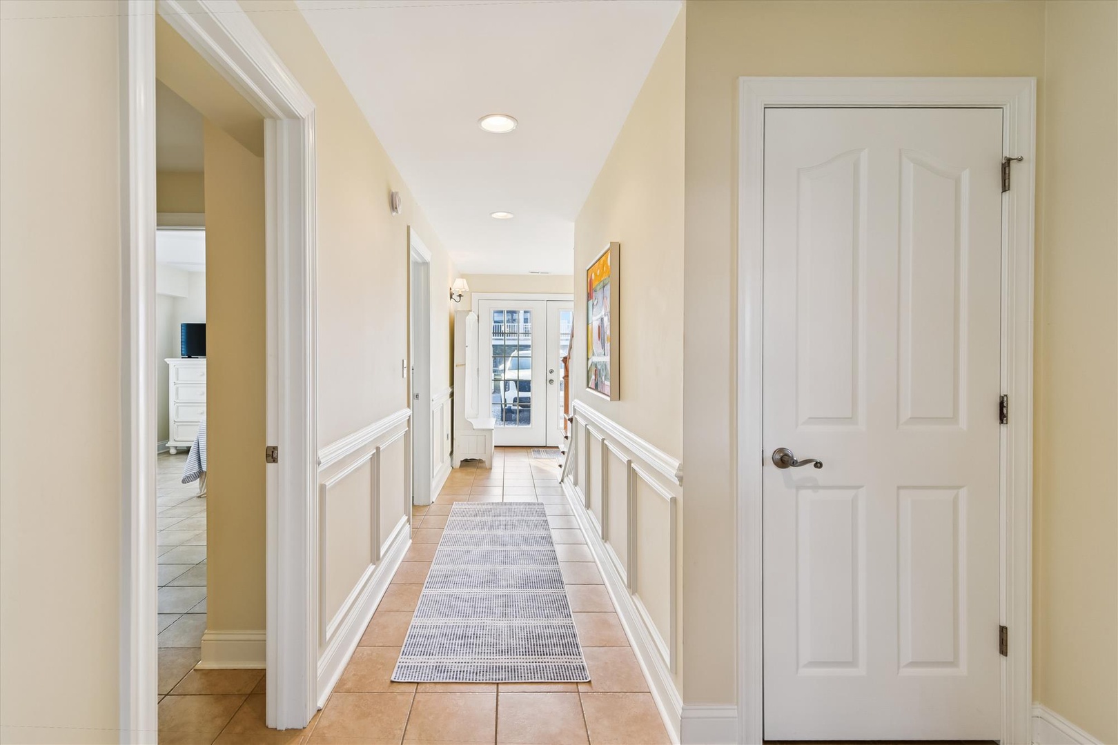 A bright, welcoming hallway guides you from the entrance to your cozy spaces, with warm tile underfoot and charming wainscoting that adds character to your vacation retreat.