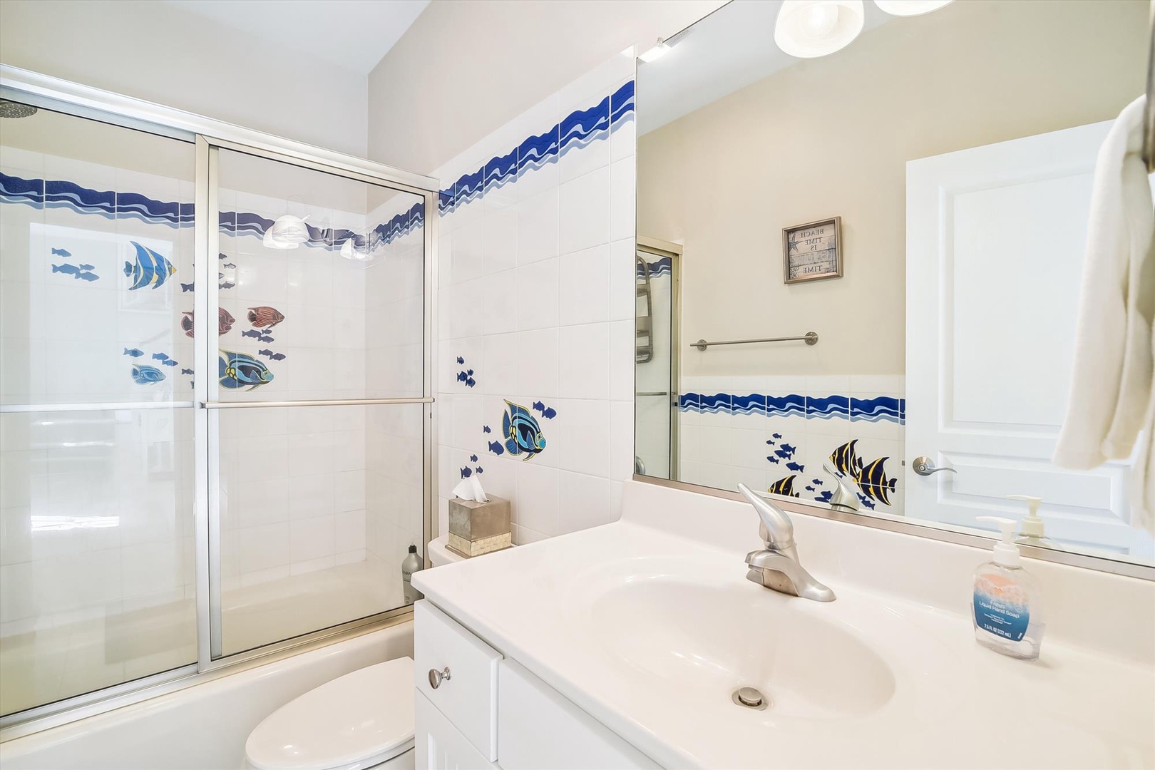 Refresh in your coastal-themed bathroom, where tropical fish tiles and a glass-enclosed shower create a breezy, beach-house vibe after your day exploring the area.