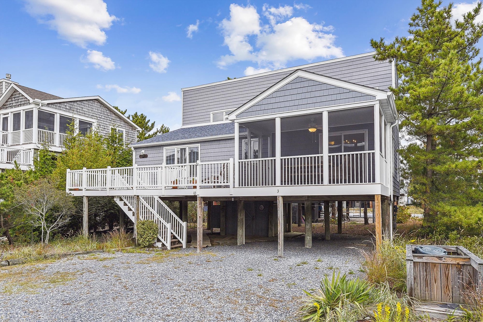 This charming coastal beach home features classic gray shingle siding, a screened porch for bug-free relaxation, and multiple decks for enjoying ocean breezes under sunny skies.