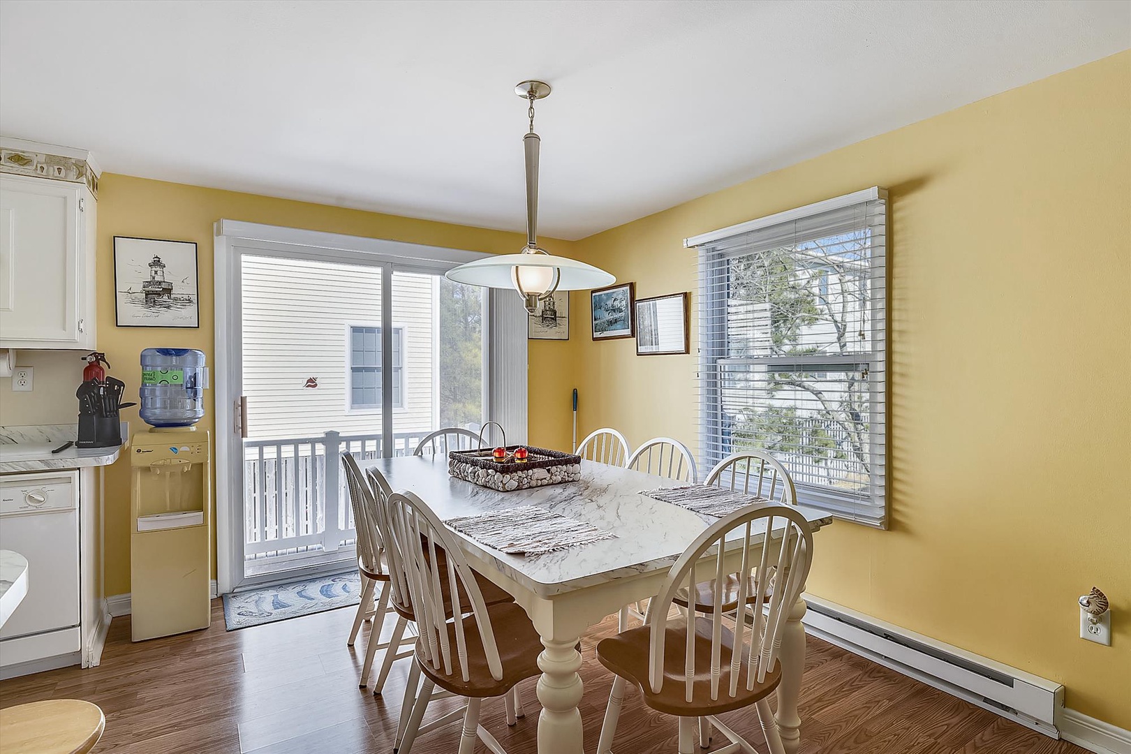 Gather around this sunlit dining table where shared meals become cherished memories. Large windows fill your dining space with natural light, and the balcony door opens to your private outdoor retreat.