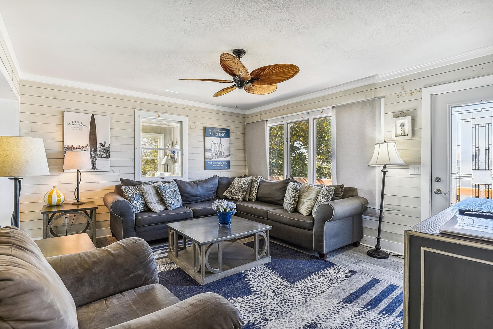 Sink into plush coastal comfort in your bright living room, where whitewashed walls, a tropical ceiling fan, and soft natural light create a relaxing retreat after your beach adventures.