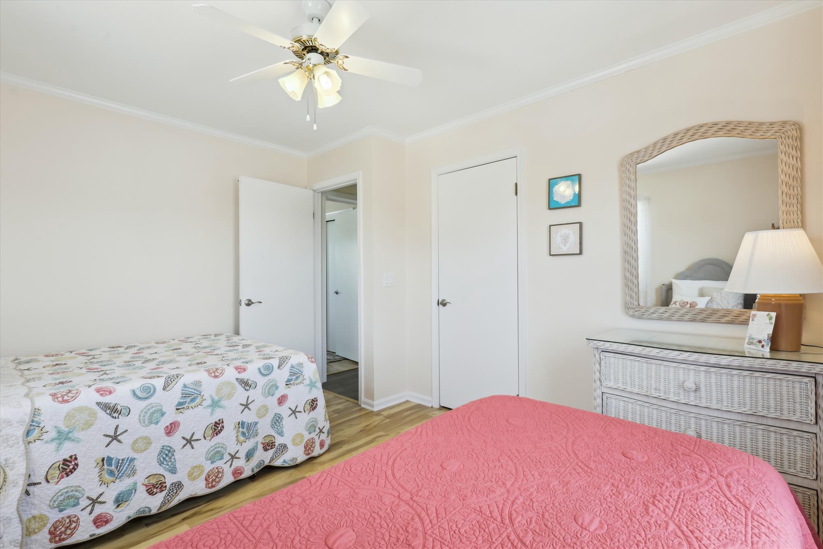 Relax in this bright, beach-inspired bedroom with two comfortable beds, coastal decor, and a ceiling fan to keep you cool. Your own private retreat awaits.