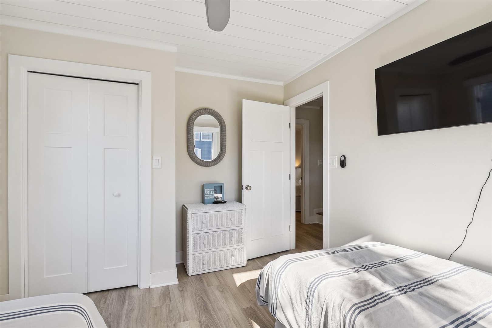 Unwind in this bright coastal bedroom with crisp white linens and soothing neutral tones. Your private retreat features dual beds, thoughtful storage, and a wall-mounted TV for relaxation.