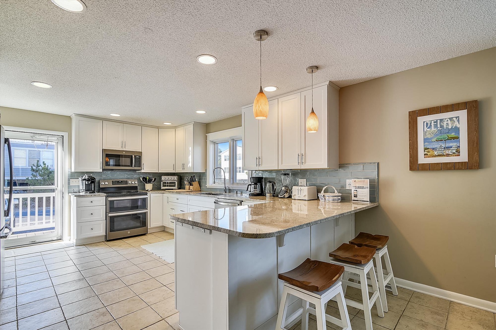 Gather around this bright, open kitchen where you can cook meals together, share stories at the island, and enjoy the coastal charm of pendant lighting and beach-inspired decor.