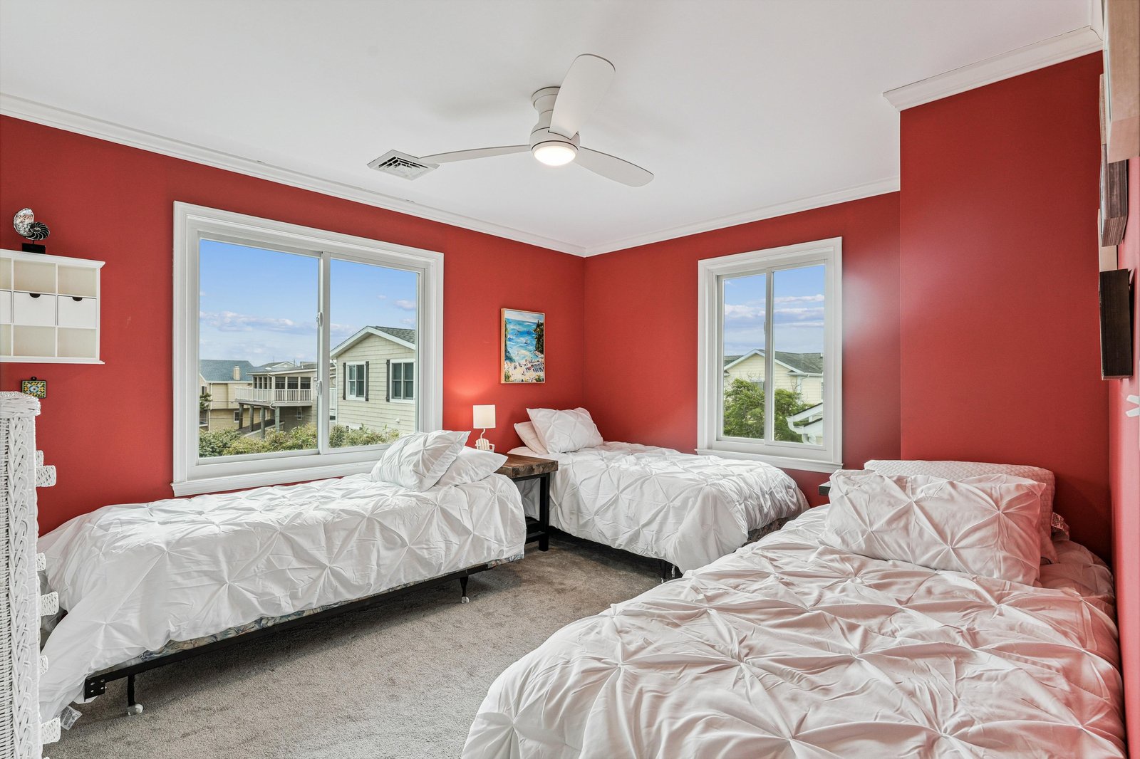Drift off in this cheerful bedroom with three cozy beds and real coastal views framing your mornings. The vibrant coral walls and plush linens invite rest after your day's adventures.