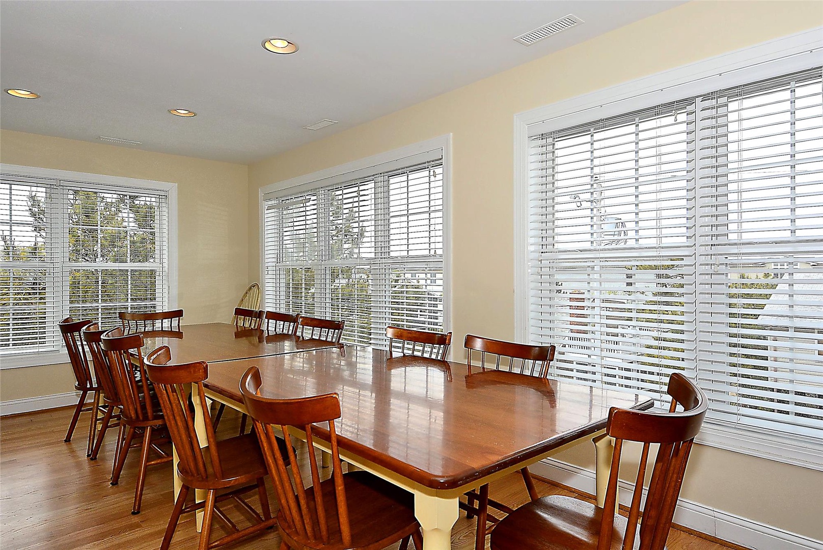 Gather around this inviting communal dining table, where natural light pours through large windows, creating a bright and welcoming space for your group meals and conversations.