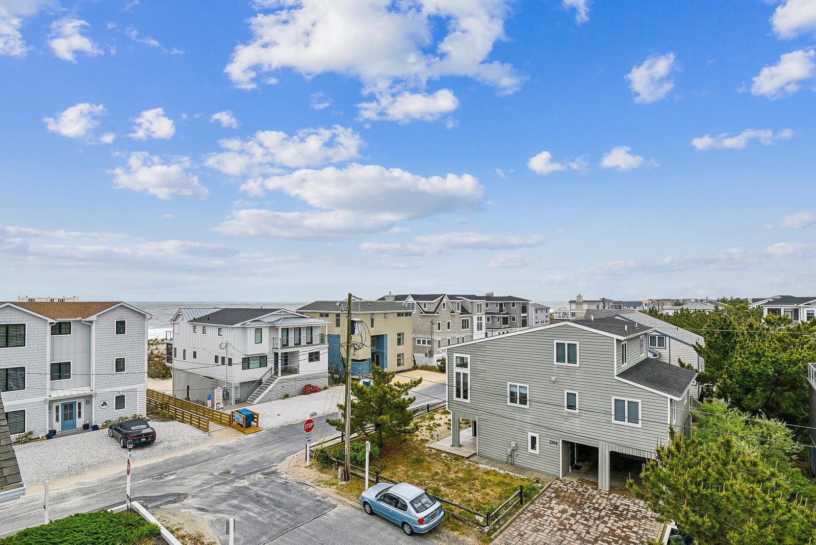 Aerial view of the property and surrounding coastal neighborhood, showing the multi-level vacation home elevated on stilts with convenient parking beneath, nestled in a peaceful beachside community.