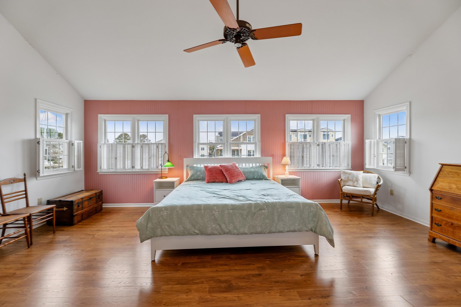 Rest easy in your spacious master suite with warm wood floors, charming coastal accents, and plenty of natural light streaming through plantation shutters.