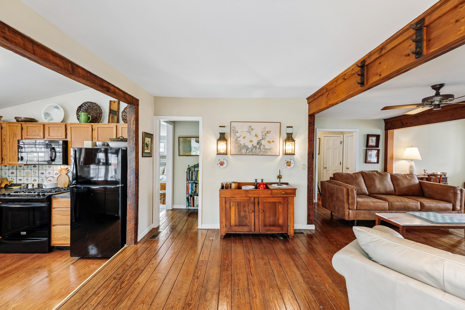 Warm open-concept retreat with rustic wooden beams, rich hardwood floors, fully equipped kitchen, and cozy leather seating—ideal for unwinding after exploring the area.
