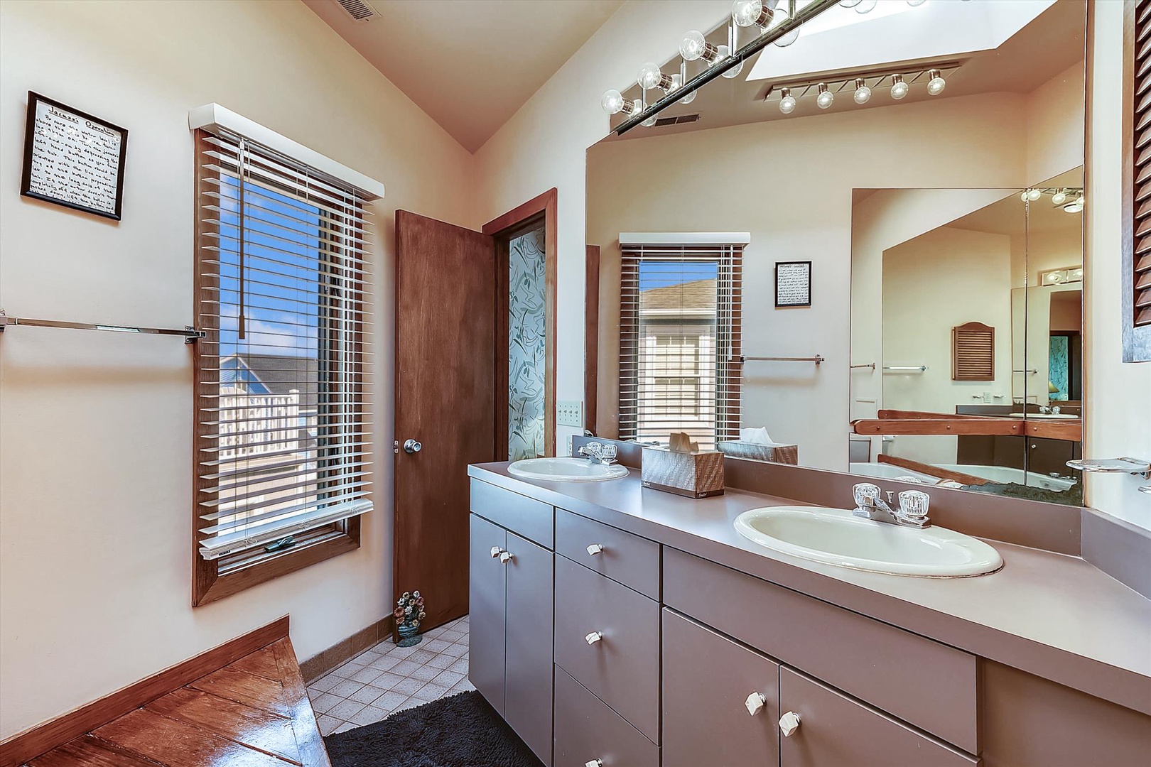 Your private bathroom features dual sinks with ample counter space, warm lighting, and natural light from dual windows—perfect for your morning routine.