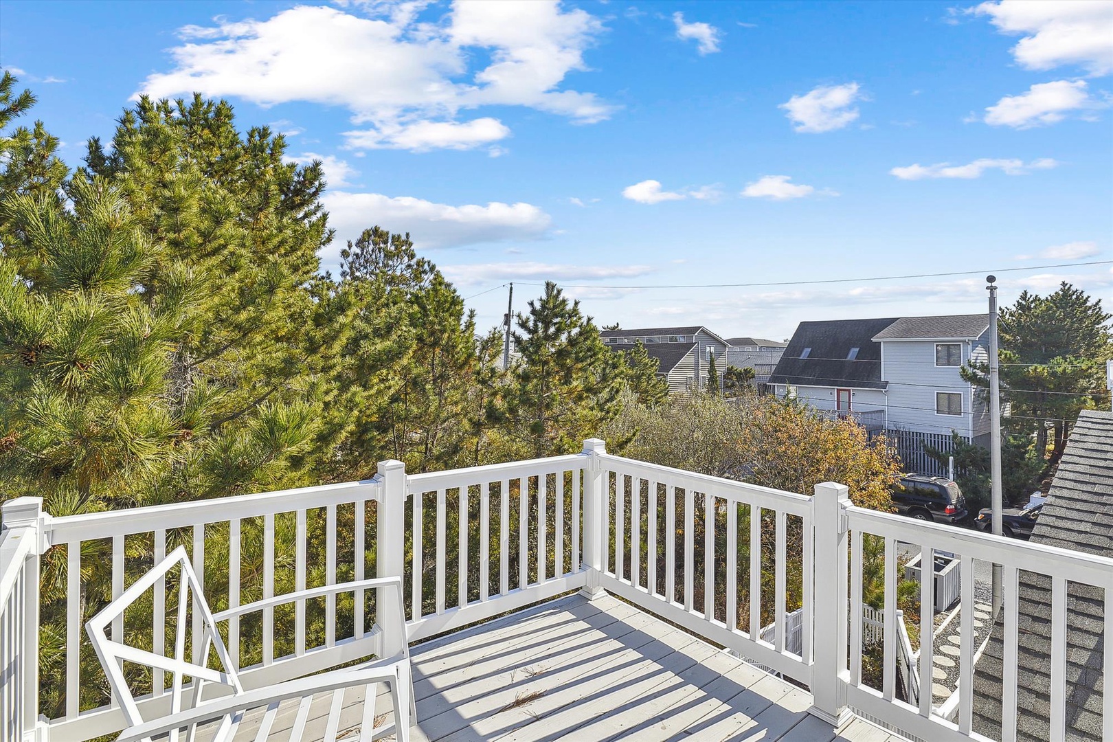 Elevated deck positioned in a residential neighborhood surrounded by mature pine trees and other homes. This outdoor space provides a peaceful area setting with natural light and tree coverage.
