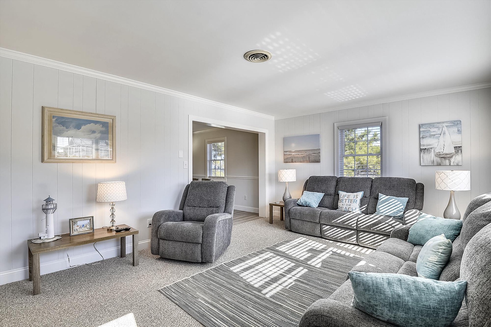 Sink into plush gray seating with coastal blue accents in your bright, open living room where natural light dances through the windows.