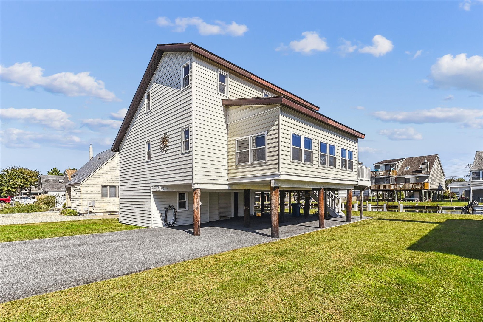 Charming coastal rental with spacious parking, surrounded by well-maintained grounds in a friendly neighborhood. The bright facade and covered carport welcome you to your waterside retreat.