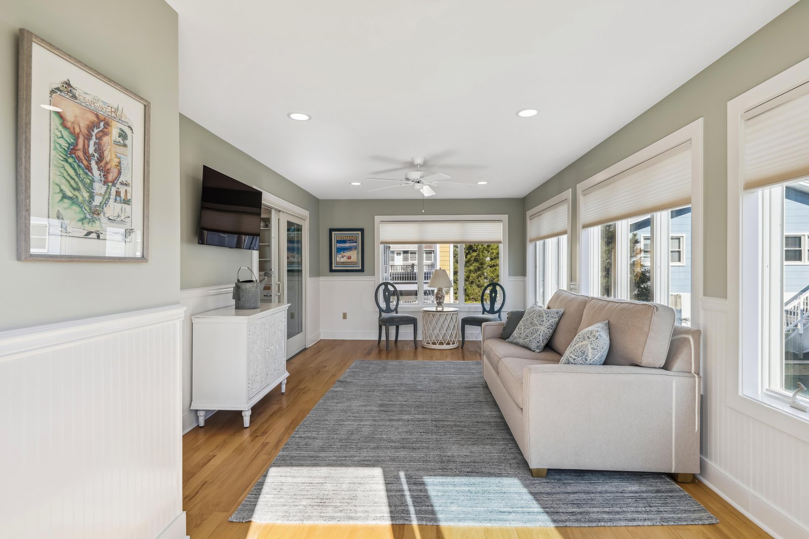 Relax in a bright, open living space where soft gray-green walls meet gleaming hardwood floors and oversized windows invite the outside in. Your sofa faces a dining nook perfect for morning coffee or afternoon wine.
