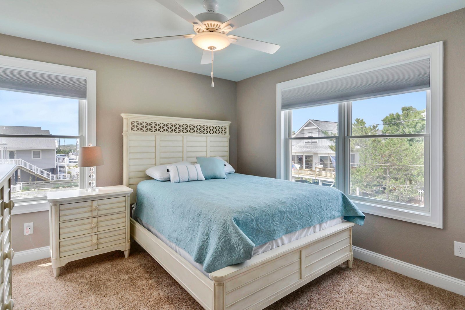 Step into your peaceful bedroom, where soft coastal blues and crisp white furniture create a soothing retreat. Gentle breezes from the ceiling fan and natural light from two windows make it easy to unwind.