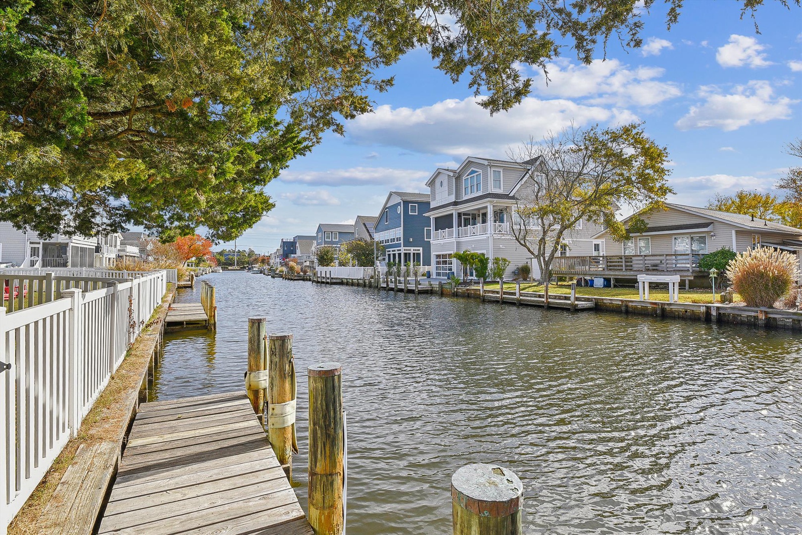 Waterfront neighborhood with canal access, private docks, and charming coastal homes nestled among mature trees under a clear autumn sky.