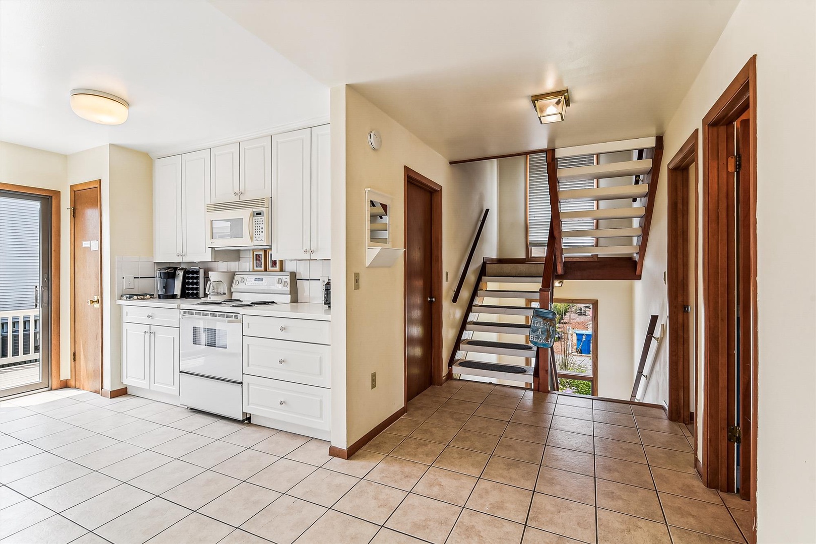 Your spacious kitchen features sleek white cabinets, modern appliances, and tile floors that flow seamlessly throughout the open living area.