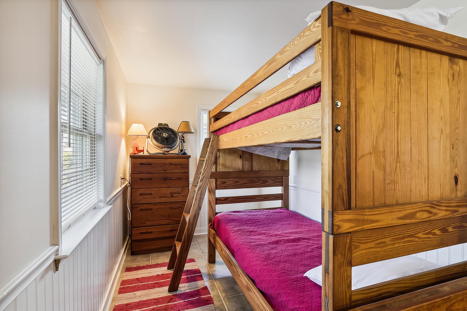 Your family will love this cozy bedroom featuring sturdy wooden bunk beds with vibrant bedding, perfect for kids to share adventures and make vacation memories together.