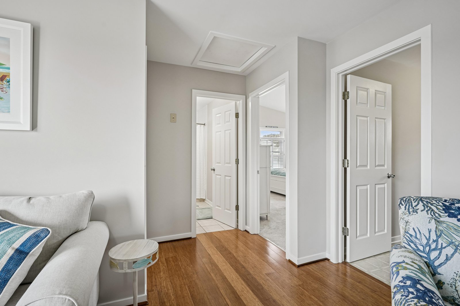 Step into your inviting living space with warm hardwood floors, soft neutral tones, and an open layout connecting your cozy seating area to private bedrooms beyond.