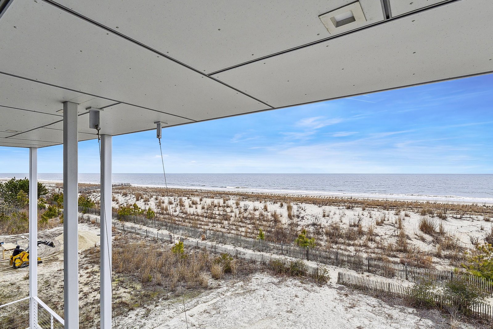 A covered outdoor terrace offers an unobstructed beachfront setting where gentle waves meet sandy shores just beyond your private space.