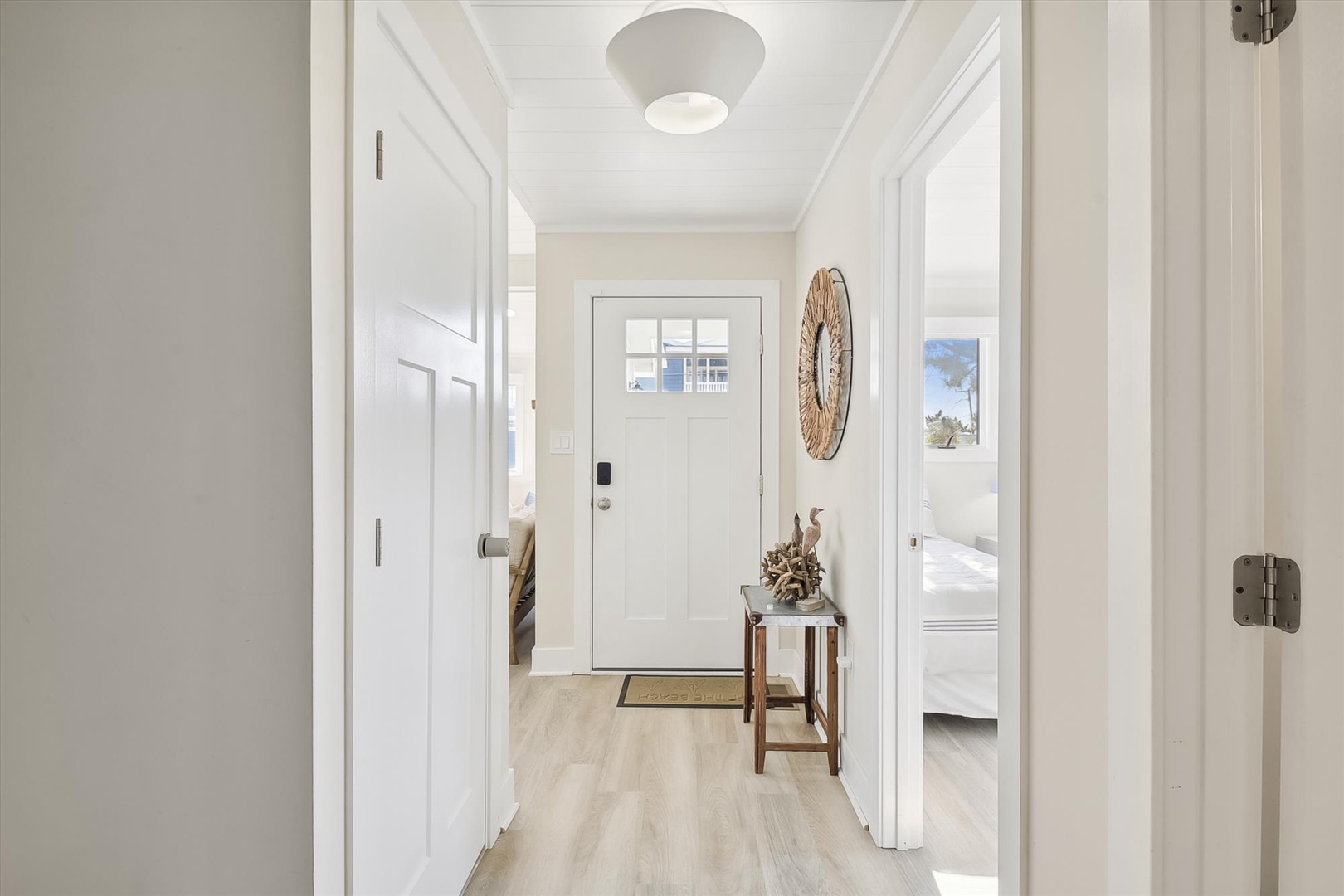 A bright, welcoming hallway greets you with soft coastal tones, warm wood accents, and thoughtful decor that makes moving between rooms feel calming and effortless.