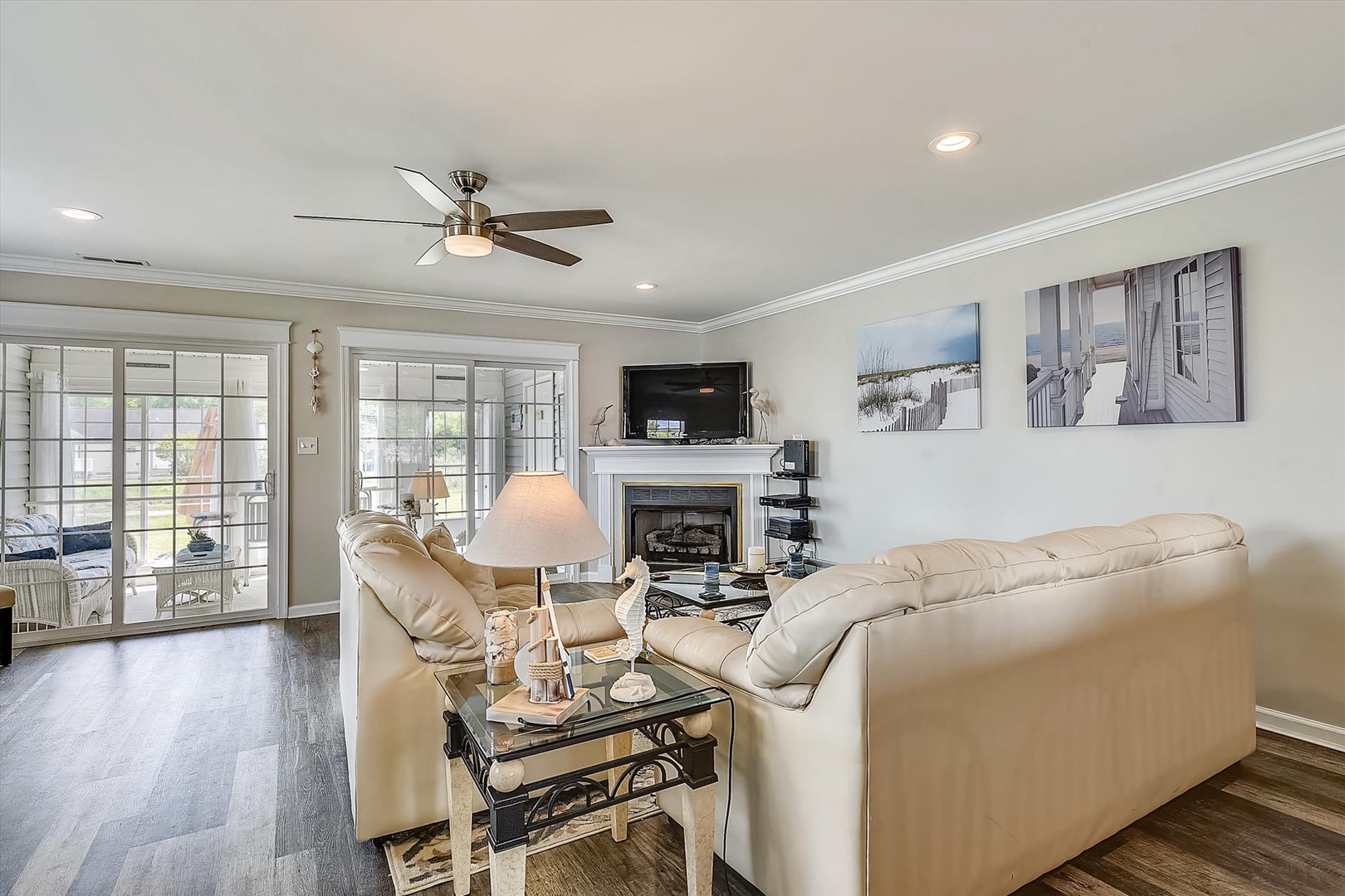 Relax in this bright, comfortable living room with plush seating, calming coastal artwork, and glass doors opening to your private outdoor patio—your perfect retreat after a day exploring.