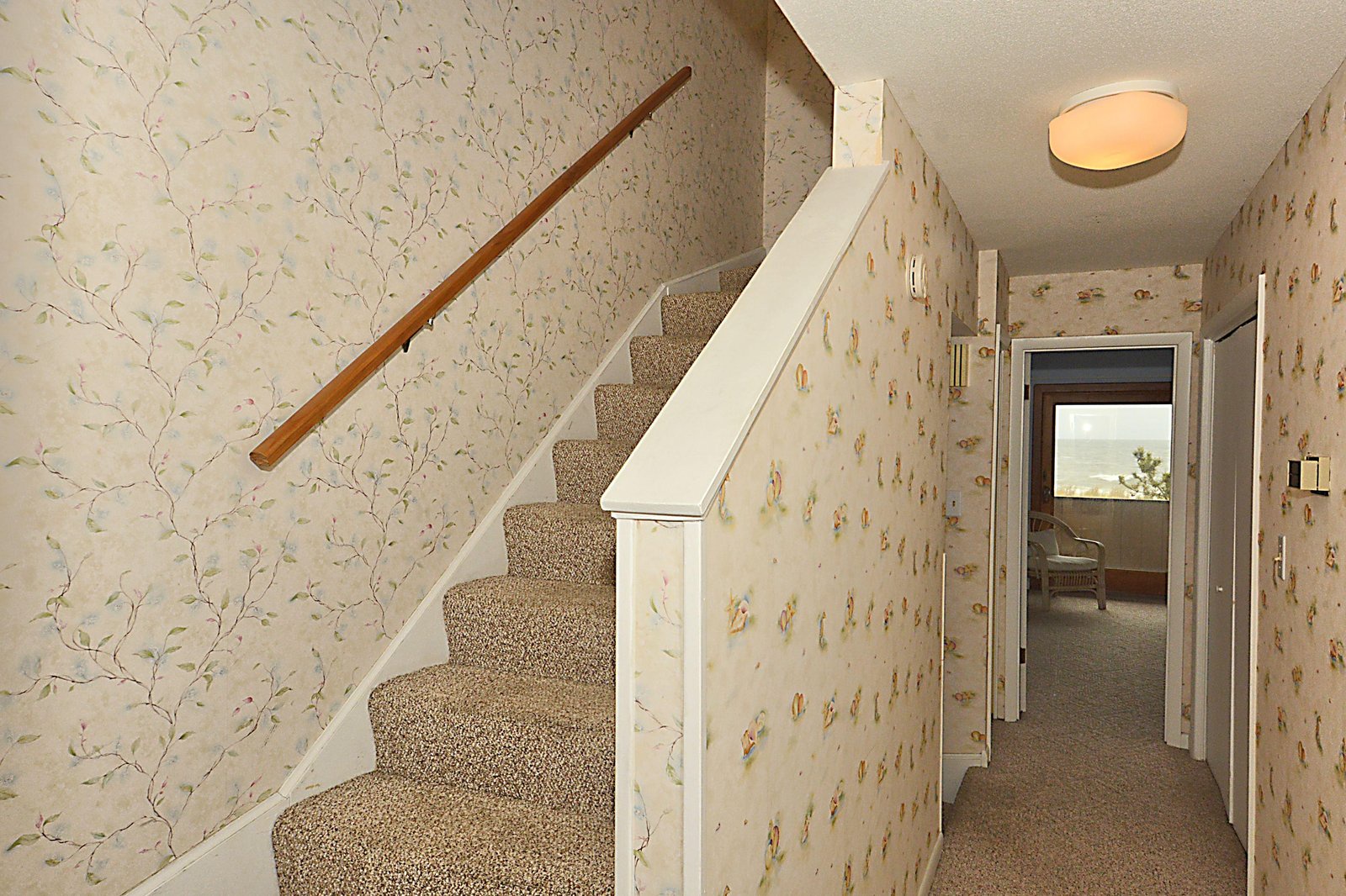 A charming stairway leads to your private retreat, while delicate floral wallpaper and warm lighting create a welcoming, homey ambiance.