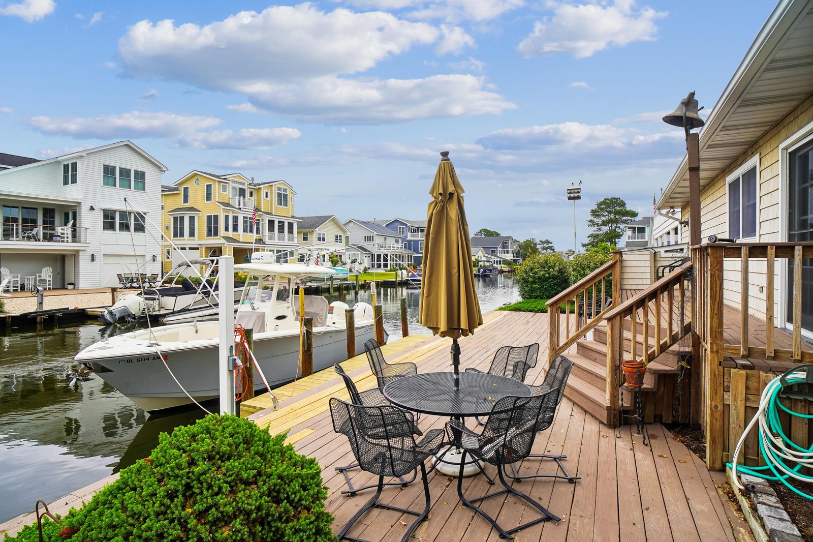 Waterfront deck with dining area and private boat slip, surrounded by coastal homes and scenic canal views—perfect for morning coffee or evening relaxation.